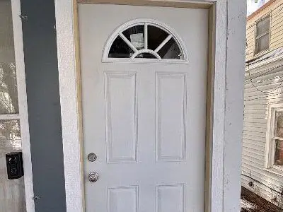 White entry door with arched window, showcasing a modern design, emphasizing insulation and security features,